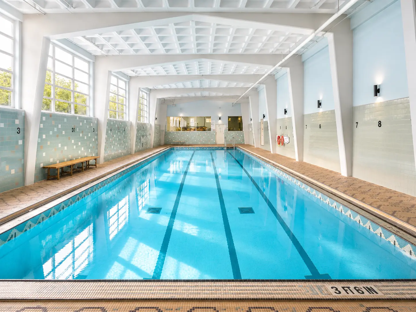 A bright four-lane indoor swimming pool with tall windows